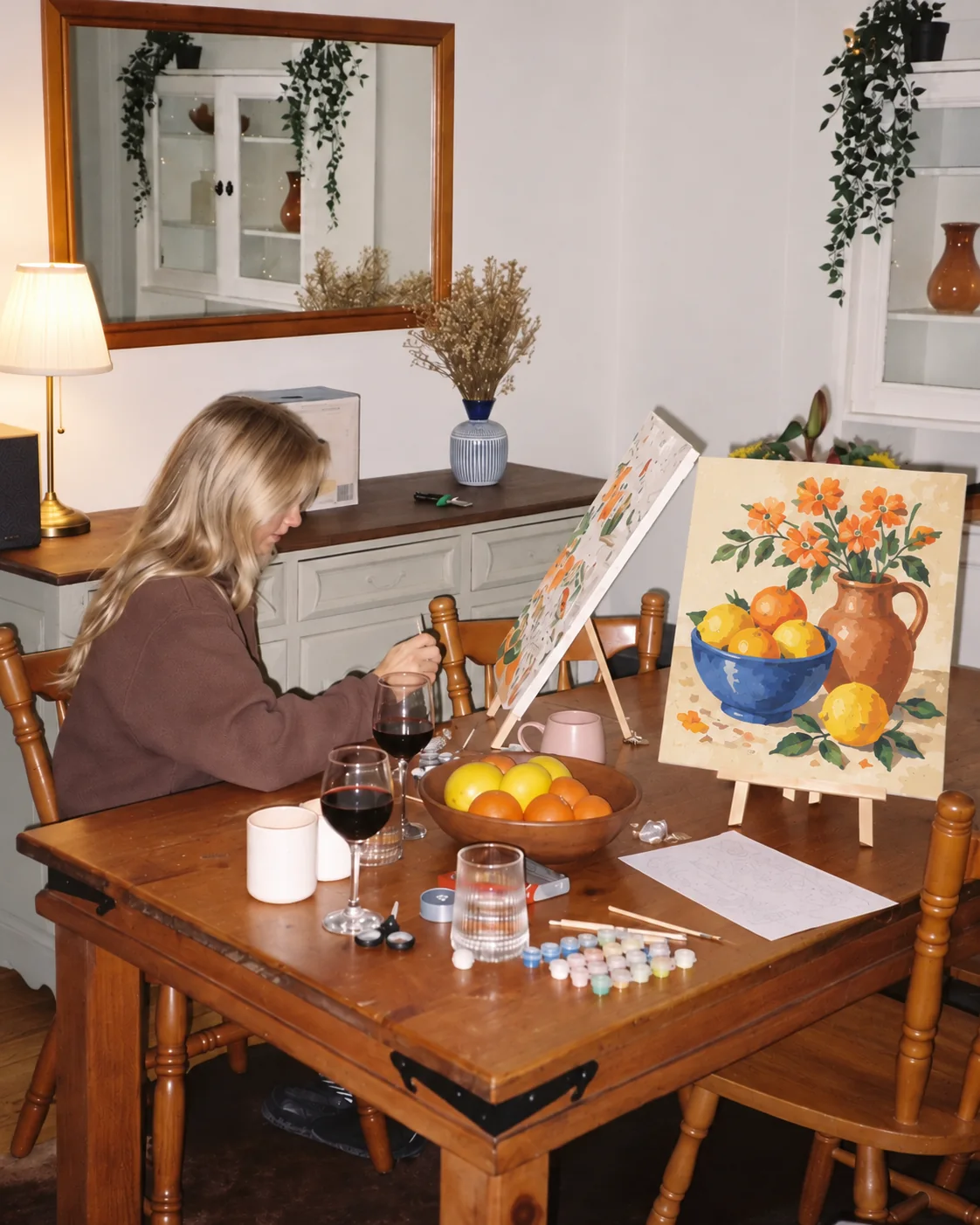 Mujer pintando un cuadro de flores y fruta por números en la mesa del comedor
